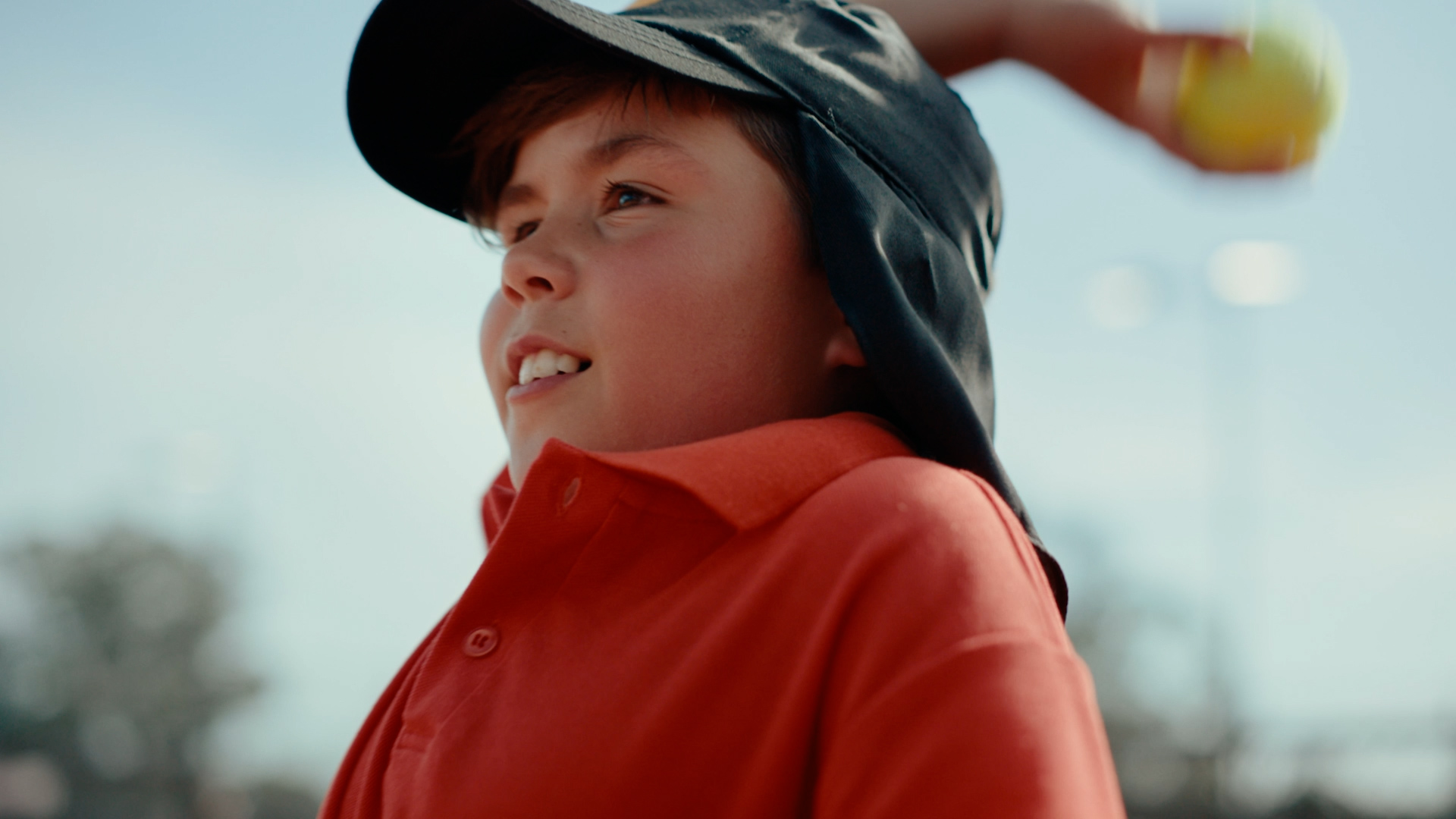 Young boy in red shirt throwing a tennis ball