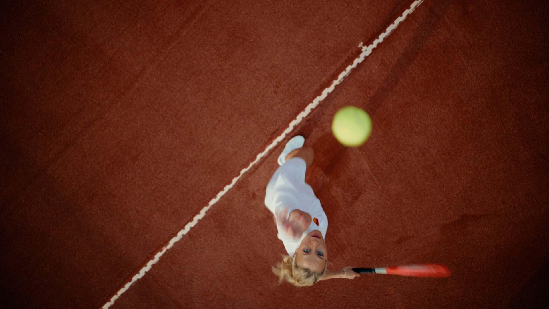 Overhead view of tennis player serving on clay court
