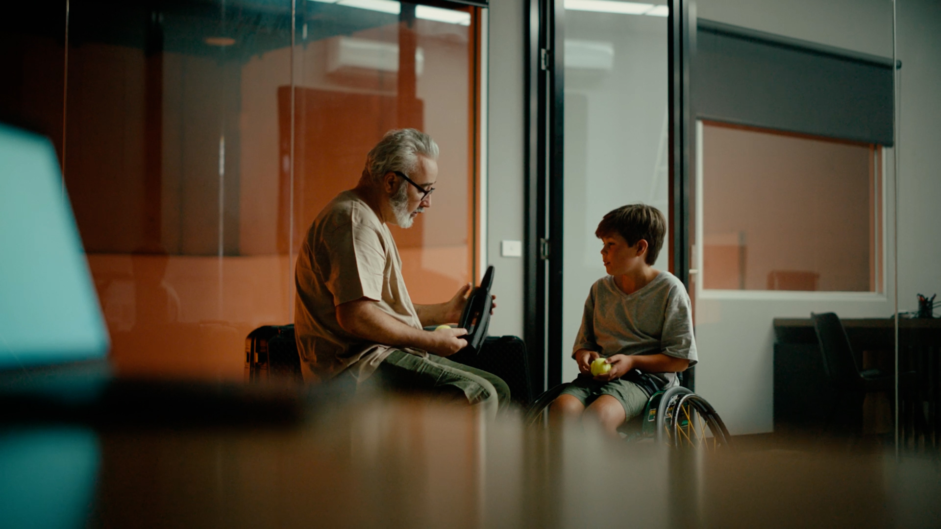 Man and boy in wheelchairs sharing a moment indoors